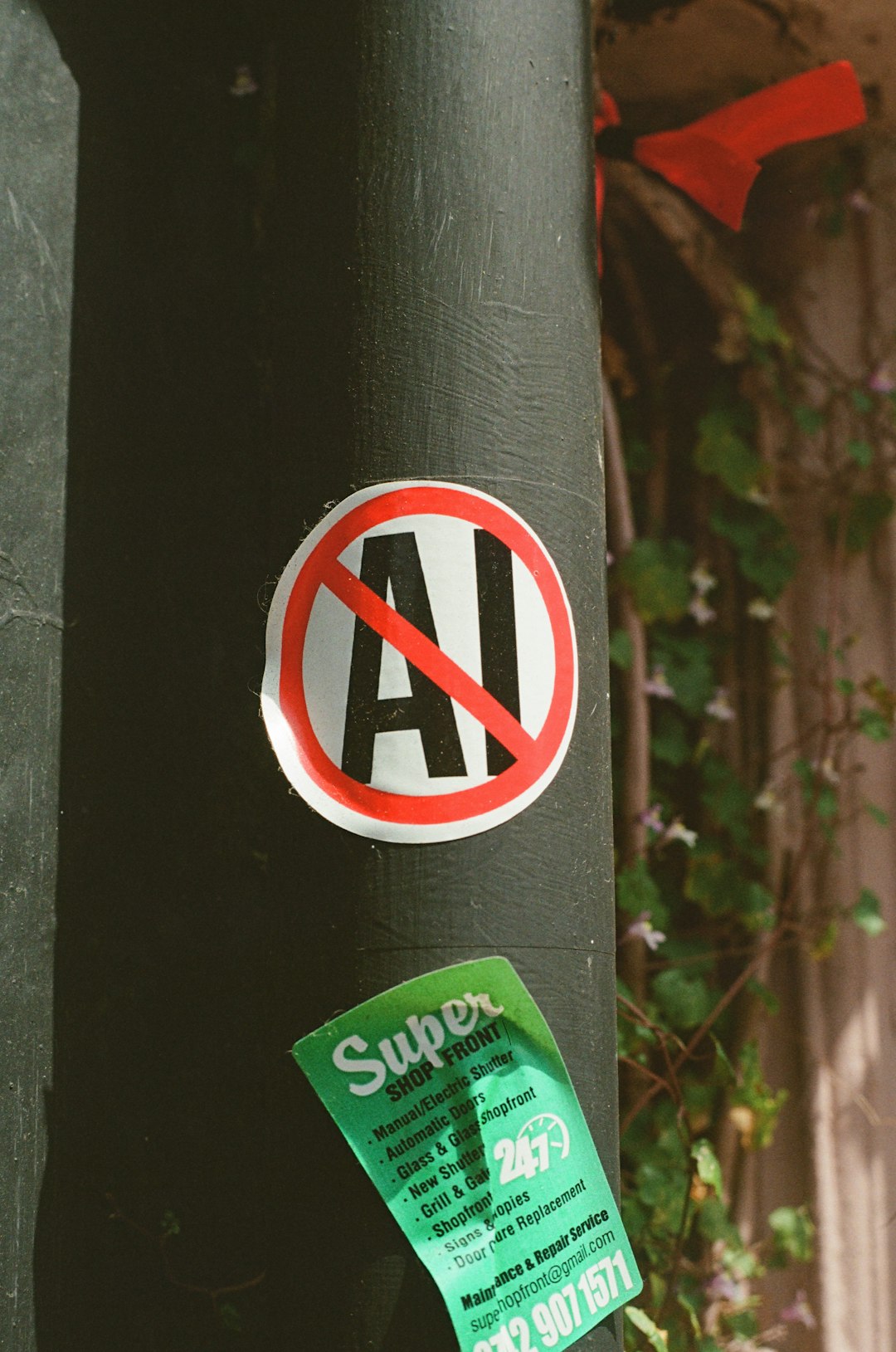 no-ai-sticker-on-a-dark-pole-with-green-advertisement-1f798xtaxc4