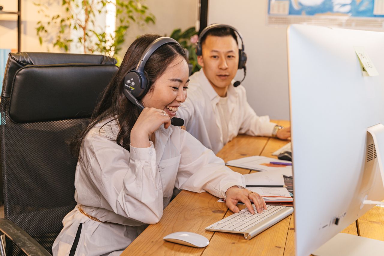 Two call center agents working together, focused and engaged at their desks, communicating via headsets.