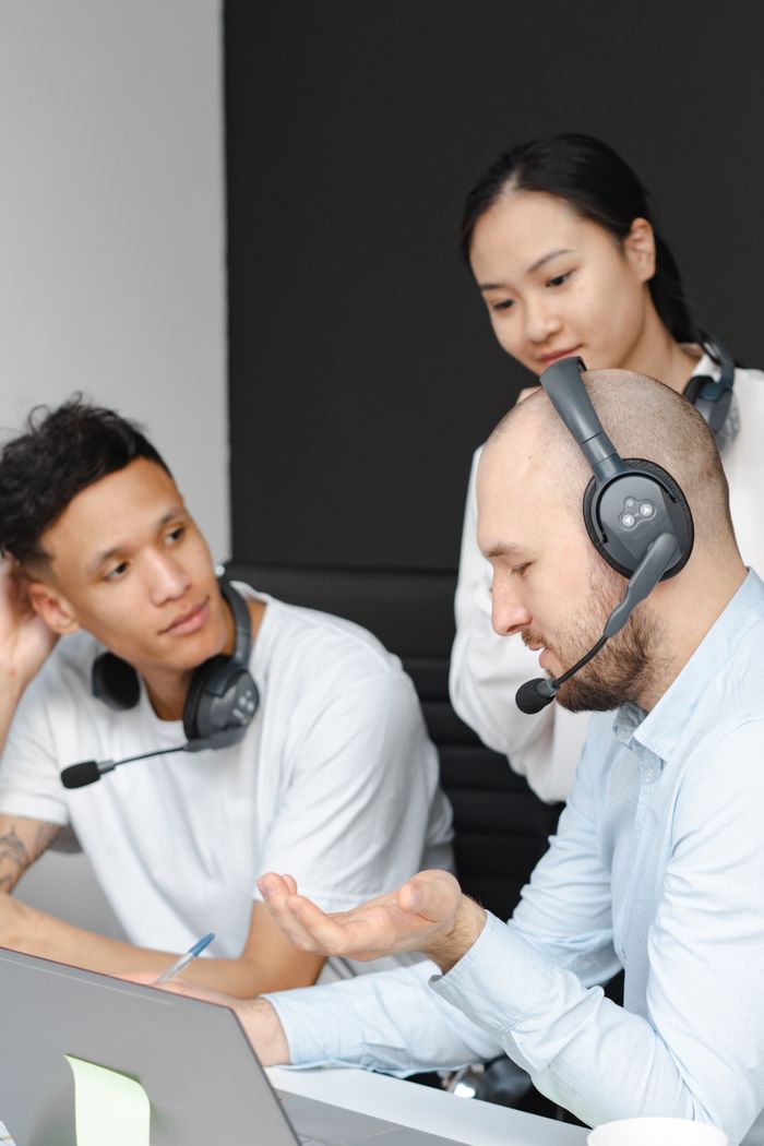 Call center agents collaborating with headsets and laptops, showcasing teamwork.